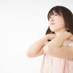 首の付け根を押さえる女性