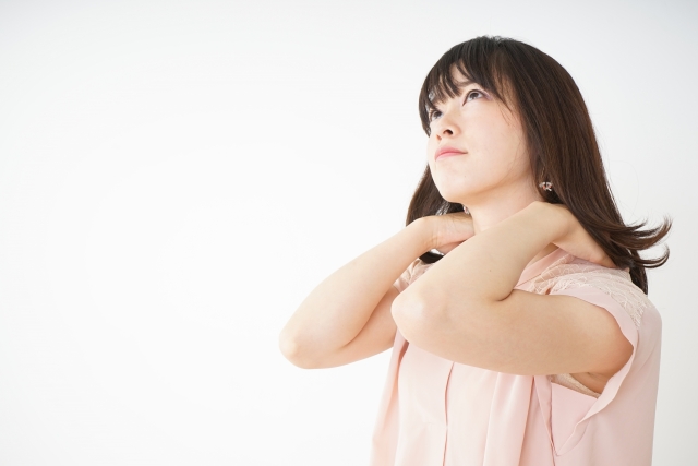 首の付け根を押さえる女性