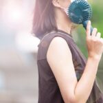 携帯用の扇風機で涼む女性