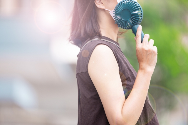 携帯用の扇風機で涼む女性